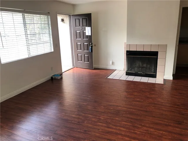 an empty room with wooden floor fireplace and windows