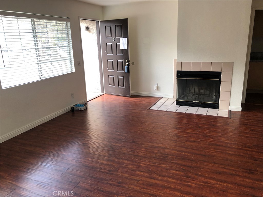 12584 Atwood Court, Unit 1824 Rancho Cucamonga, CA 91739 - Photo 4 of 15 an empty room with wooden floor fireplace and windows