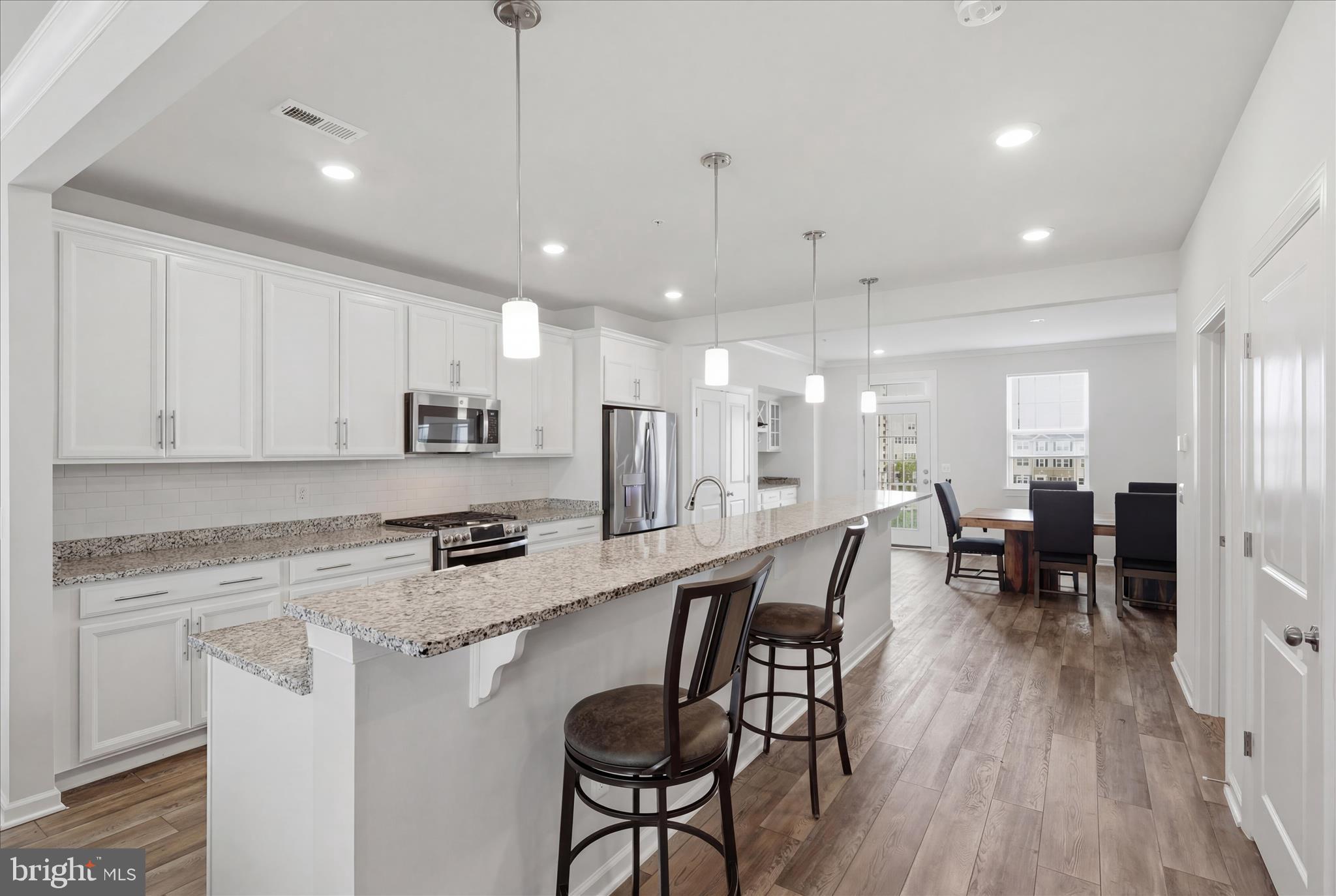 4932 MacDonough Place Frederick, MD 21703 - Photo 19 of 70 a kitchen with stainless steel appliances granite countertop a stove top oven a refrigerator a sink and chairs