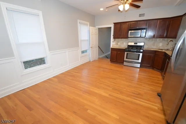 a large white kitchen with stainless steel appliances wooden floor and a refrigerator