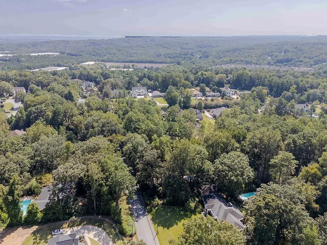 an aerial view of residential house with outdoor space and trees all around