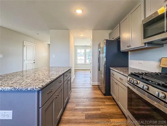 a kitchen with stainless steel appliances granite countertop a stove a sink and a microwave