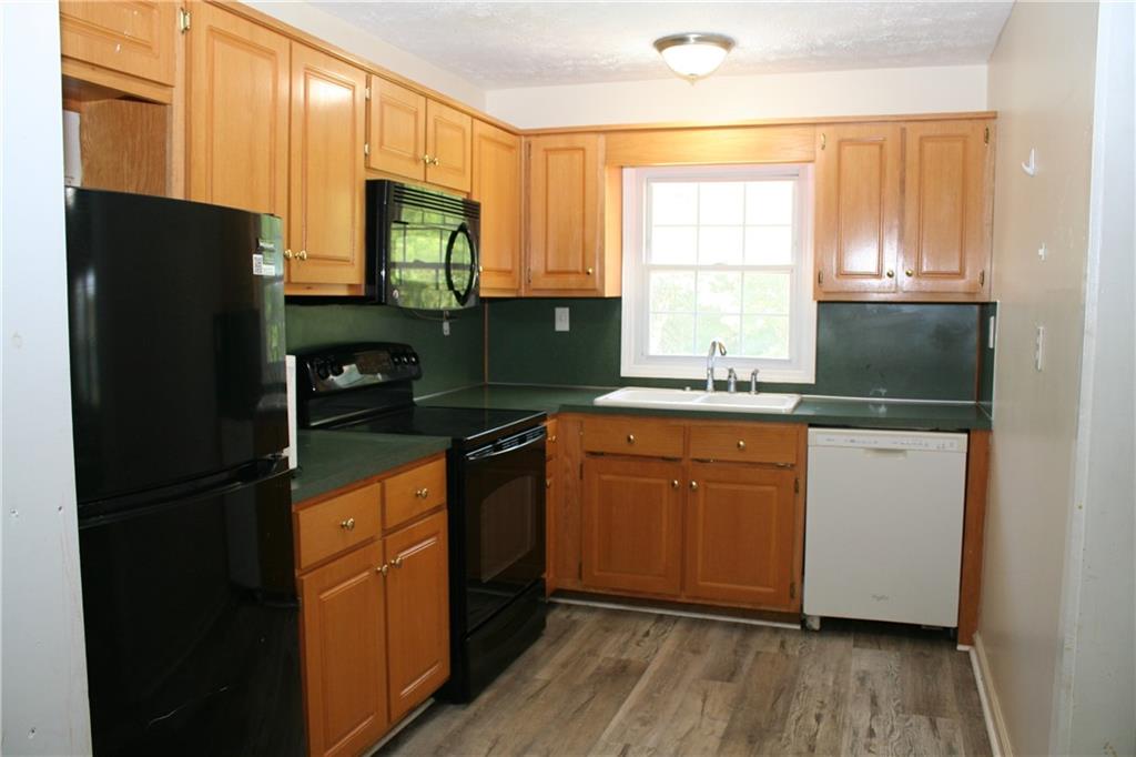 3735 South Seale Road Phenix City, AL 36869 - Photo 18 of 27 Kitchen with black appliances, light wood finished floors, dark countertops, and tasteful backsplash