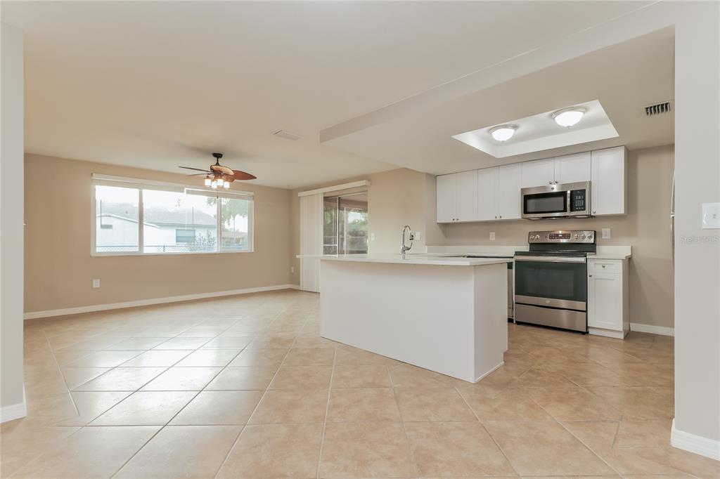 4153 Woodtrail Boulevard New Port Richey, FL 34653 - Photo 5 of 16 a kitchen with stainless steel appliances a stove sink and microwave
