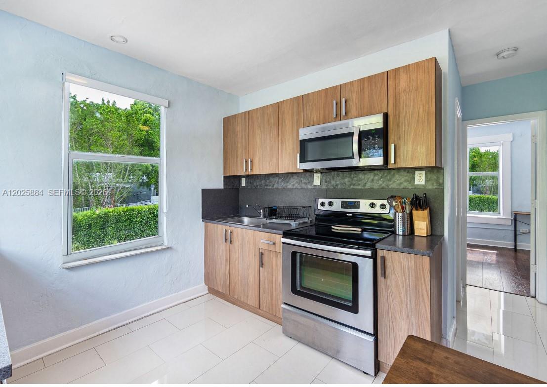 2255 Southwest 10th Street, Unit B Miami, FL 33135 - Photo 16 of 26 a kitchen with granite countertop wooden cabinets stainless steel appliances and a window