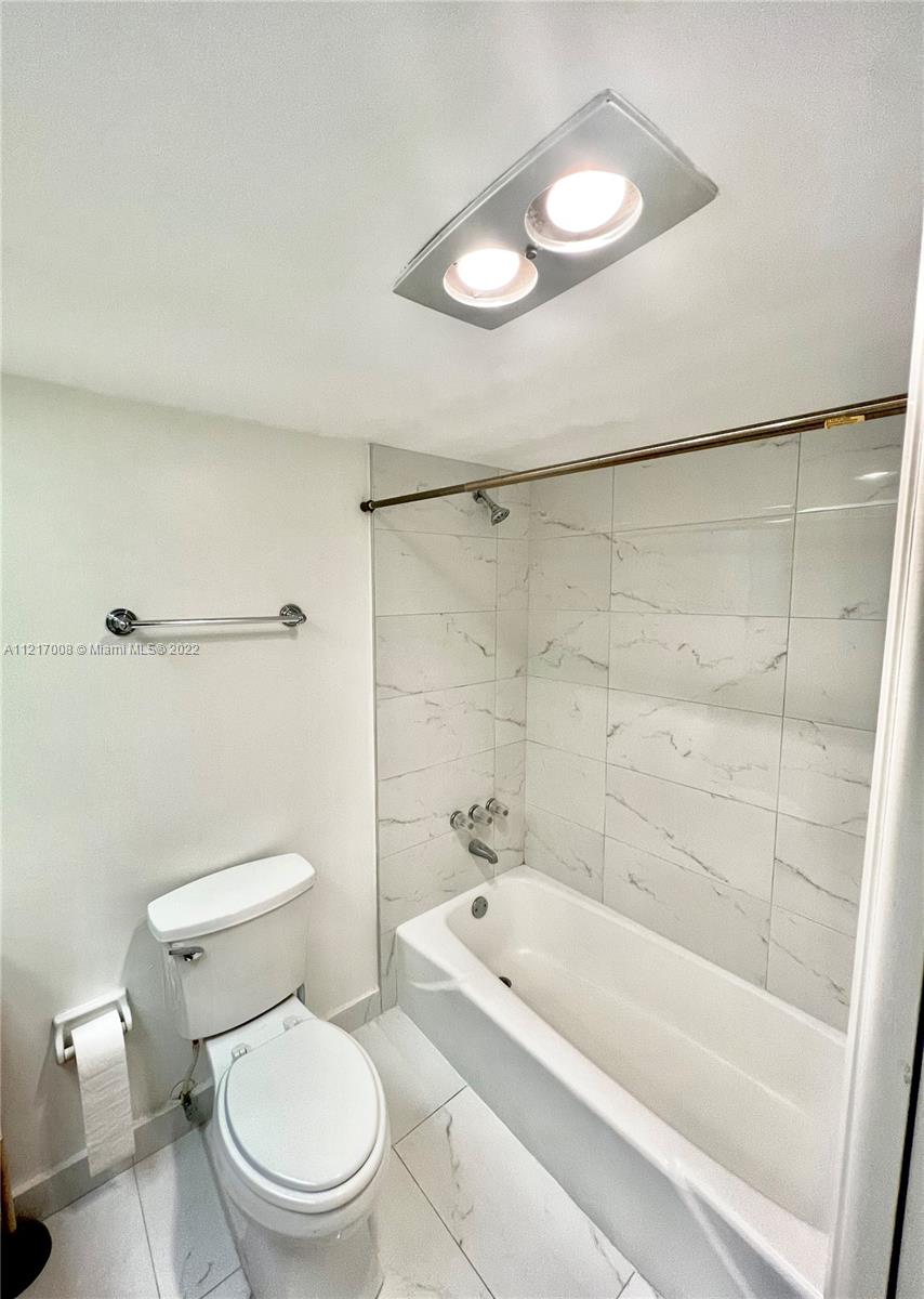 3150 North Course Lane, Unit 107 Pompano Beach, FL 33069 - Photo 16 of 24 a white toilet sitting next to a bath tub and a shower