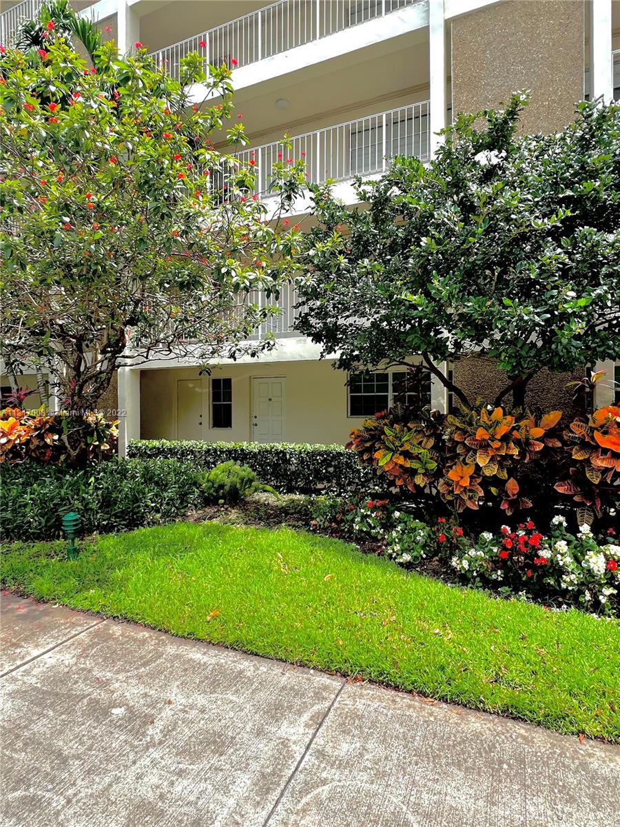 3150 North Course Lane, Unit 107 Pompano Beach, FL 33069 - Photo 3 of 24 a front view of a house with a garden and yard