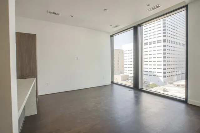 a view of an empty room with a window and wooden floor