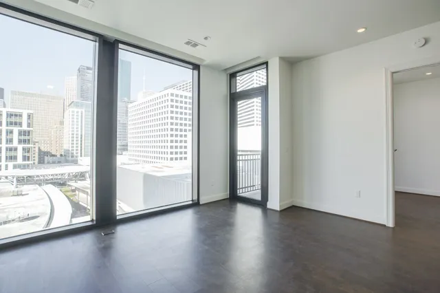a view of an empty room with a window and wooden floor