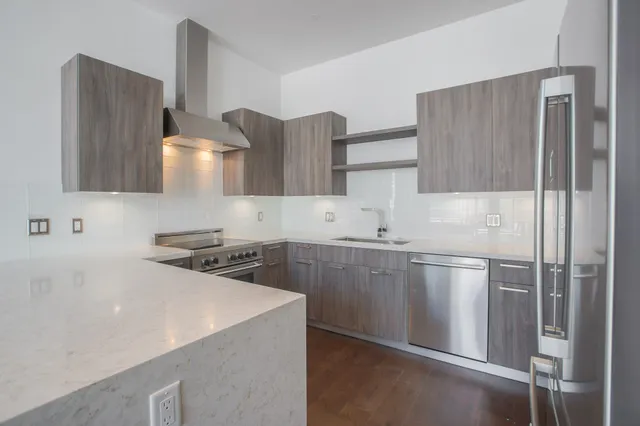 a kitchen with stainless steel appliances a sink a stove a refrigerator and cabinets