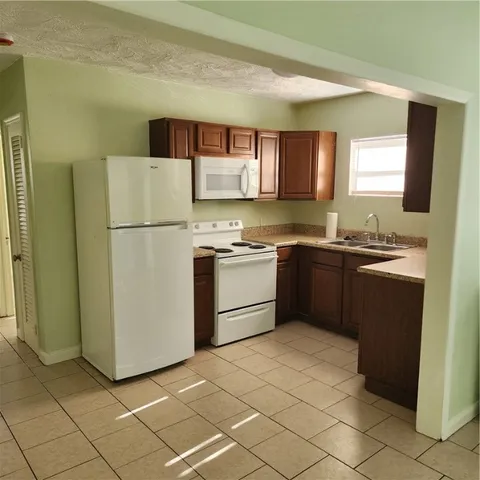 a kitchen with cabinets a sink and white stainless steel appliances