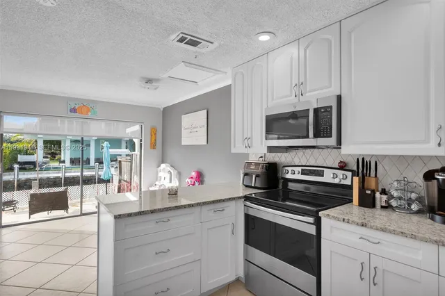a kitchen with granite countertop white cabinets and appliances