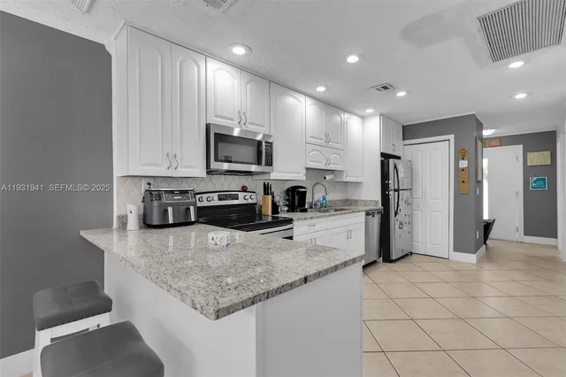 a large kitchen with stainless steel appliances granite countertop a sink refrigerator and microwave