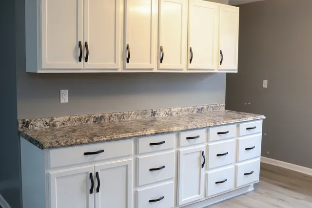 a kitchen with granite countertop white cabinets and a wooden floor
