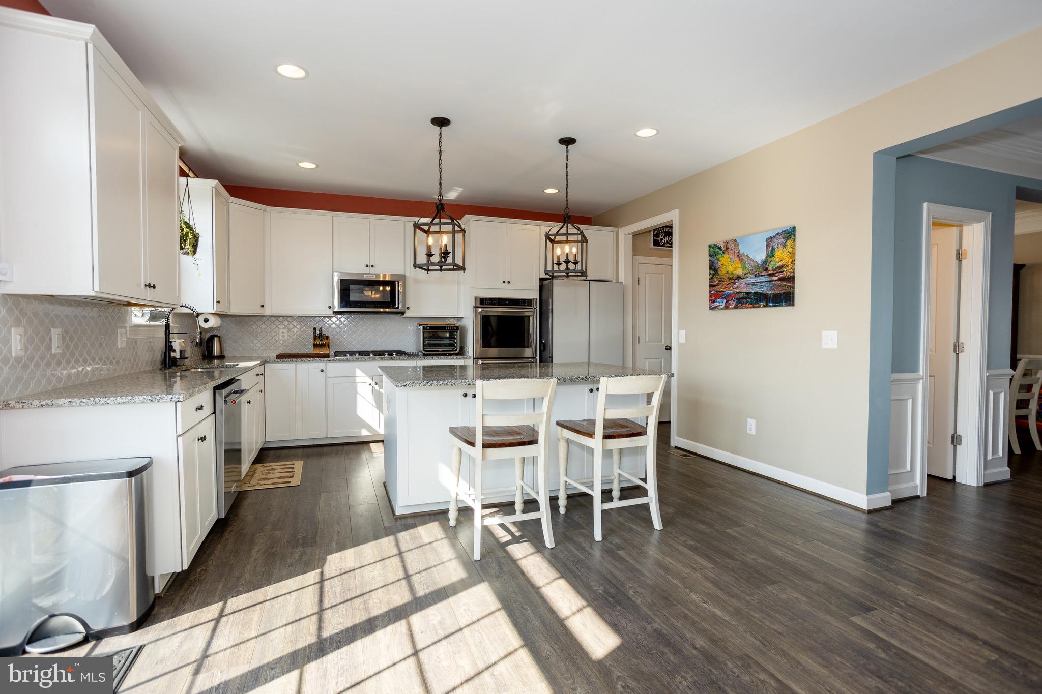 2425 Morgans Point Drive Dumfries, VA 22026 - Photo 24 of 99 a kitchen with stainless steel appliances kitchen island granite countertop a stove a sink a dining table and chairs with wooden floor