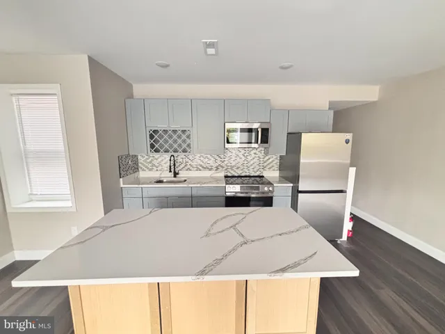 a living room with stainless steel appliances furniture a fireplace and a large window