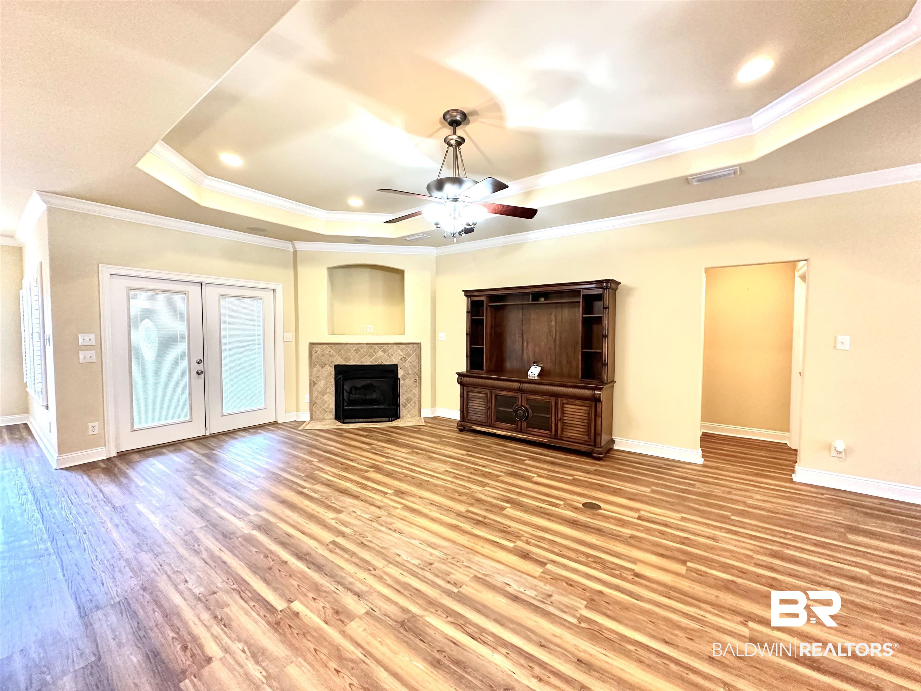 249 Hemingway Loop Foley, AL 36535 - Photo 5 of 33 Unfurnished living room with crown molding, a raised ceiling, light hardwood / wood-style floors, and ceiling fan