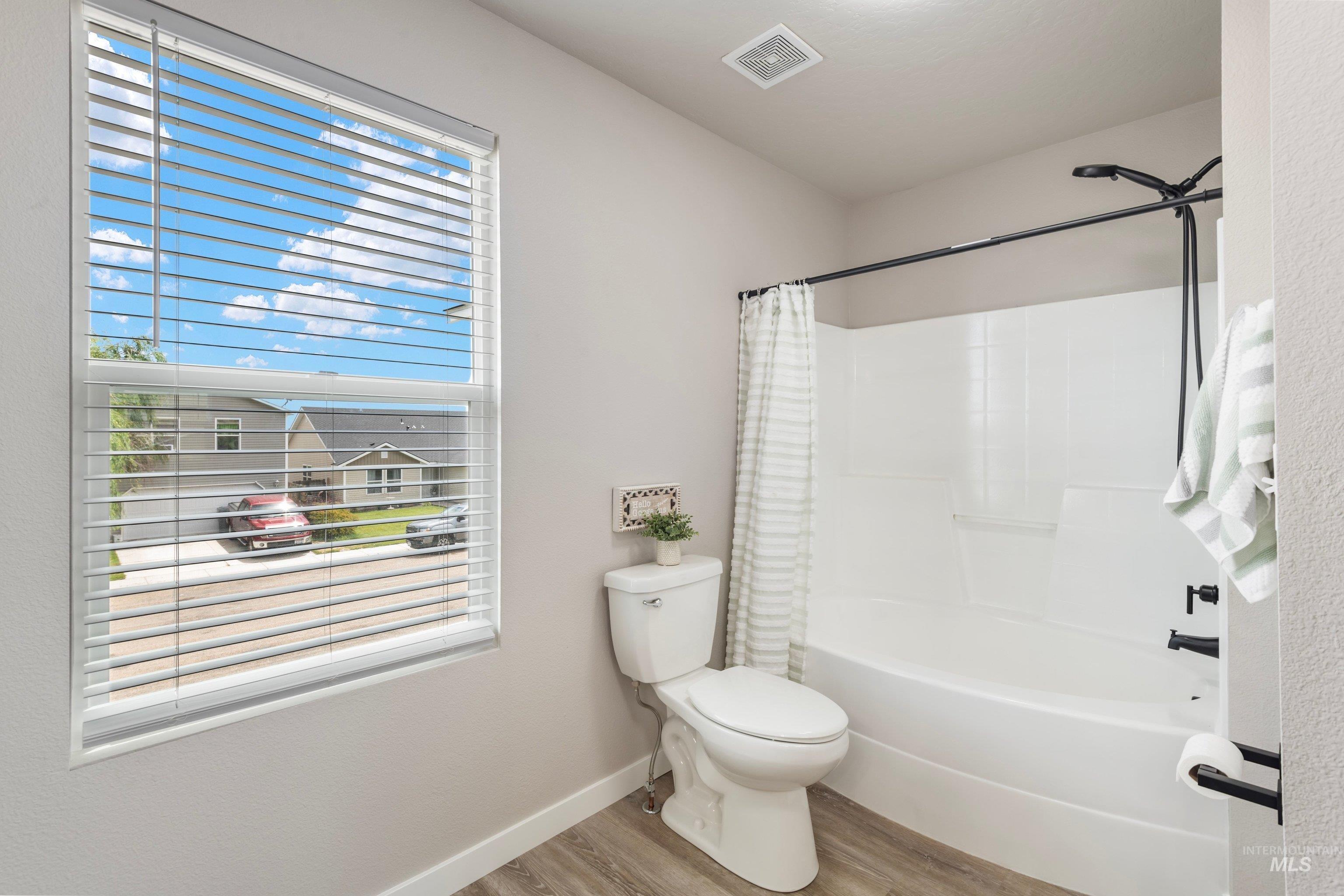 16759 Abram Avenue Caldwell, ID 83607 - Photo 17 of 33 Bathroom featuring a white tub/shower combination with matte black fixtures, a white toilet, and wood-finish flooring