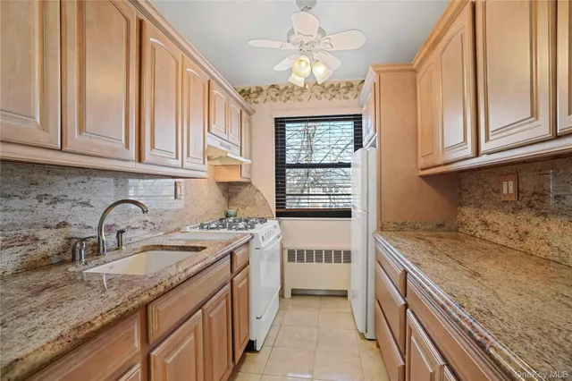 a kitchen with granite countertop a sink stainless steel appliances white cabinets and a window