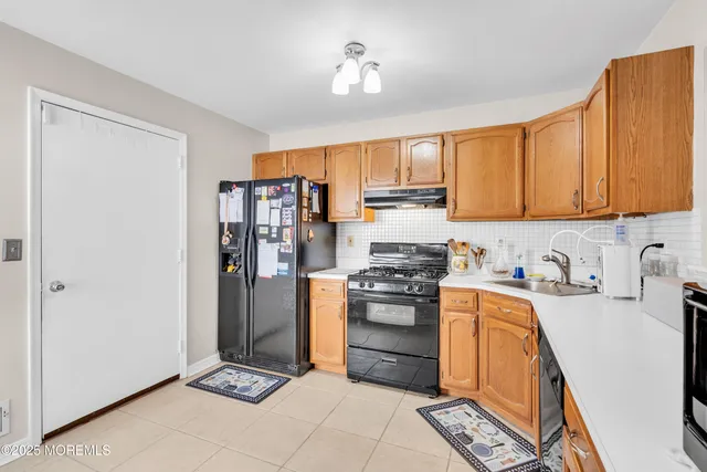 a kitchen with stainless steel appliances granite countertop a stove top oven a refrigerator a sink and dishwasher with white cabinets