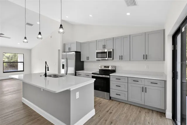 a view of kitchen with stainless steel appliances granite countertop a refrigerator a stove a sink dishwasher and a oven with wooden floor