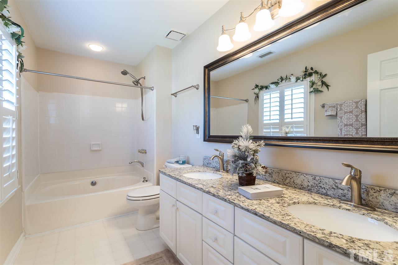 8612 Swarthmore Drive Raleigh, NC 27615 - Photo 29 of 30 a bathroom with a granite countertop double vanity sink a mirror and a bathtub