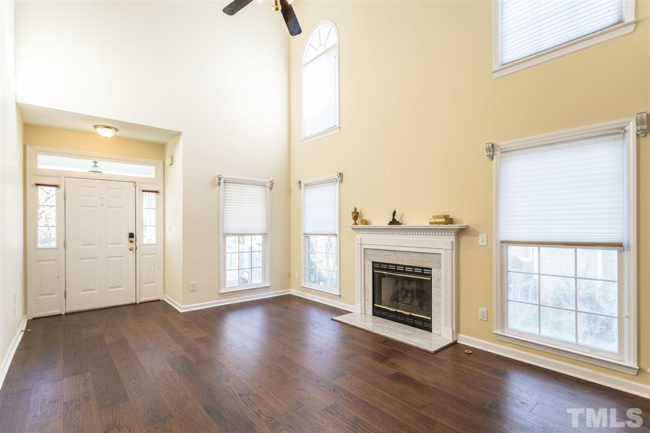 8612 Swarthmore Drive Raleigh, NC 27615 - Photo 8 of 30 an empty room with wooden floor fireplace and windows