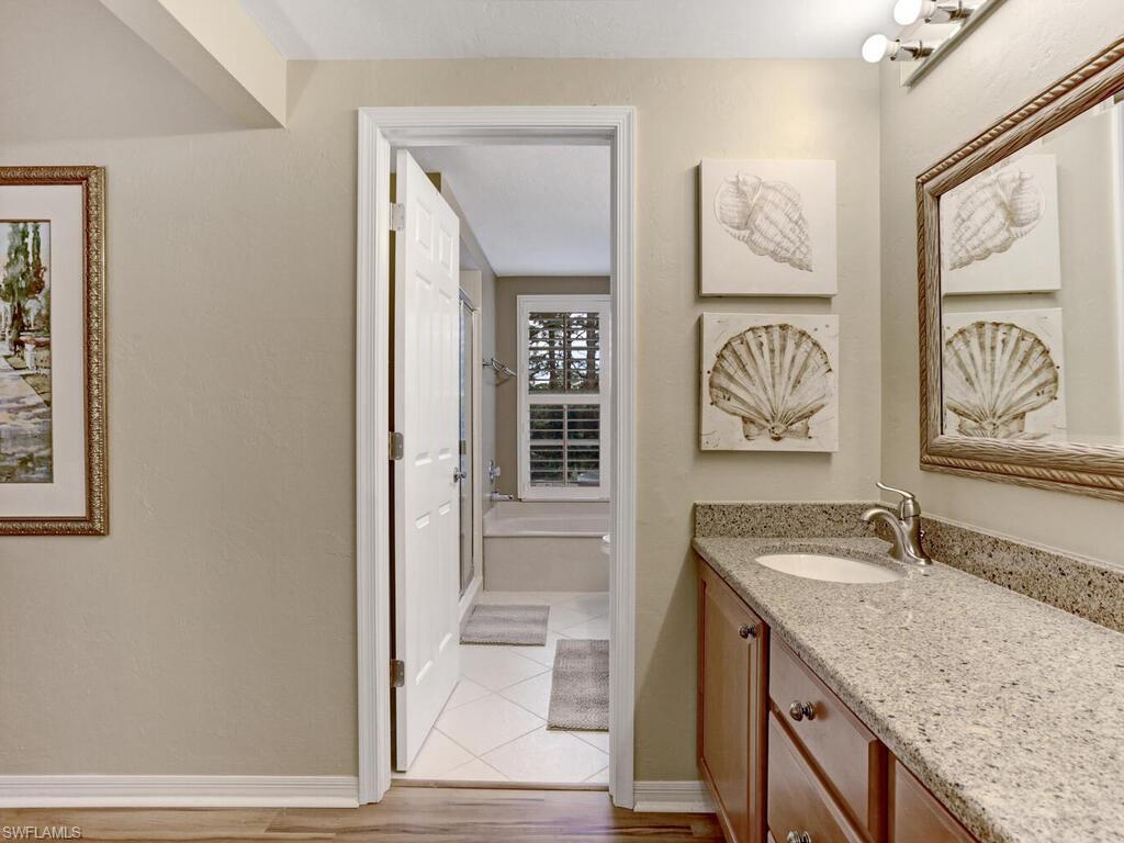 352 Bay Forest Drive, Unit 103 Naples, FL 34110 - Photo 17 of 30 a bathroom with a granite countertop sink and a mirror