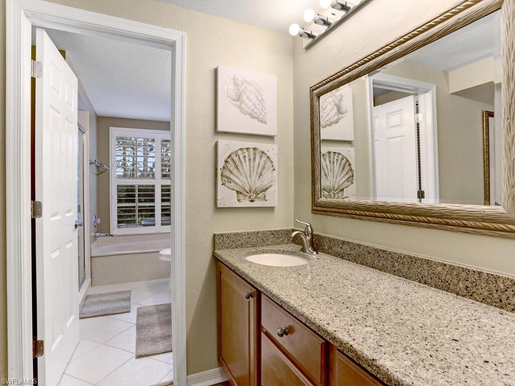 352 Bay Forest Drive, Unit 103 Naples, FL 34110 - Photo 18 of 30 a bathroom with a granite countertop sink and a mirror