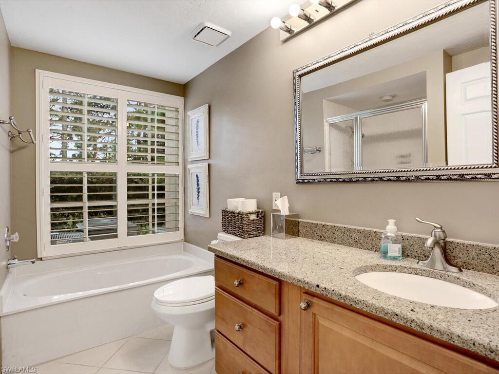 352 Bay Forest Drive, Unit 103 Naples, FL 34110 - Photo 20 of 30 a bathroom with a granite countertop double vanity sink a mirror and a bathtub