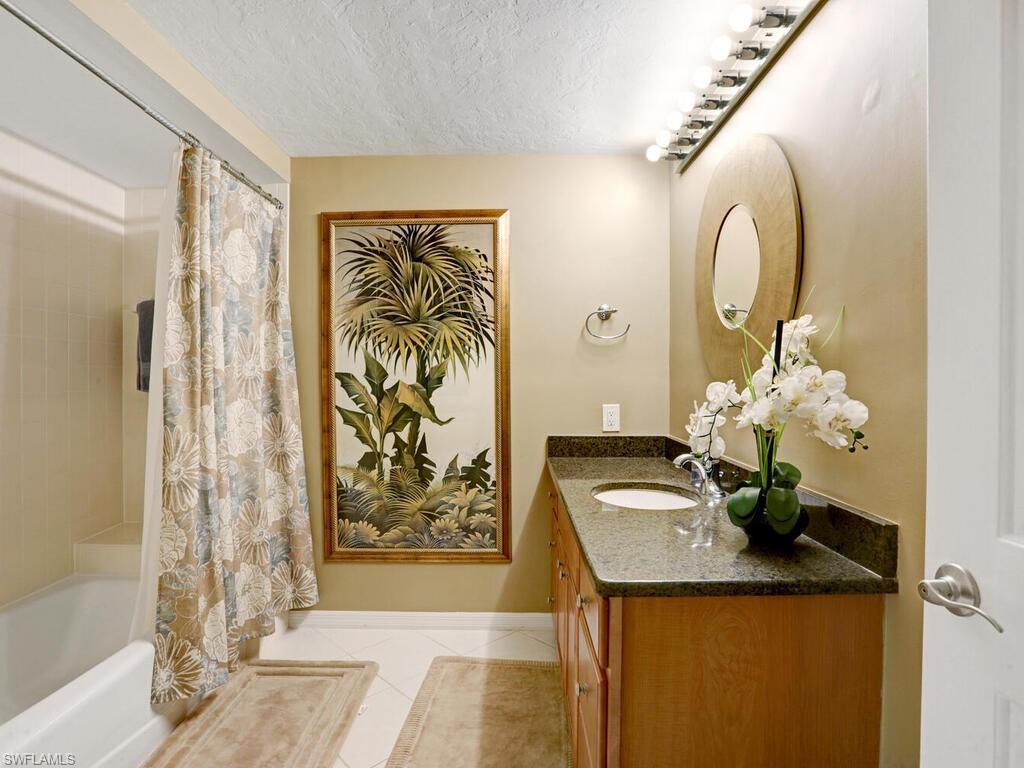 352 Bay Forest Drive, Unit 103 Naples, FL 34110 - Photo 23 of 30 a bathroom with a granite countertop sink a large mirror and a shower