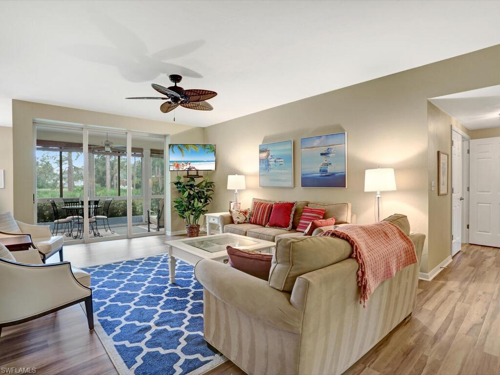 352 Bay Forest Drive, Unit 103 Naples, FL 34110 - Photo 6 of 30 a living room with furniture a large window and a chandelier