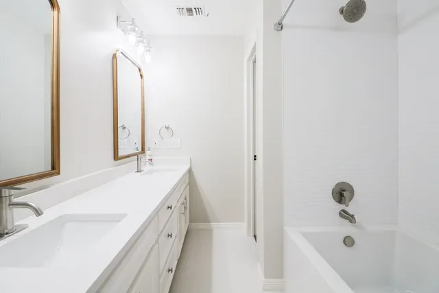 a bathroom with a double vanity sink a mirror and a bathtub