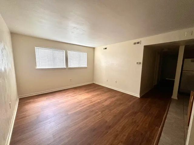 an empty room with wooden floor and windows