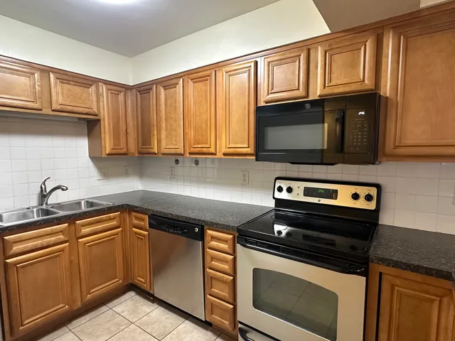a kitchen with granite countertop a stove microwave and sink