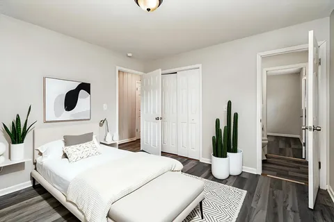 a bedroom with a bed and a potted plant on the dresser