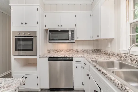 a kitchen with stainless steel appliances granite countertop a sink a stove and microwave