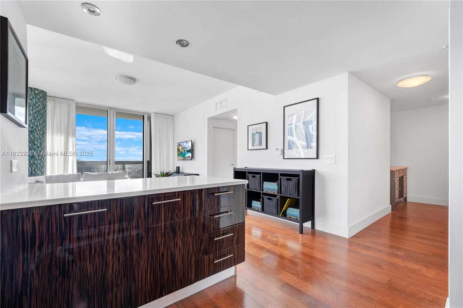 6899 Collins Avenue, Unit 1409 Miami Beach, FL 33141 - Photo 22 of 35 a kitchen with stainless steel appliances granite countertop a sink and wooden cabinets with wooden floors