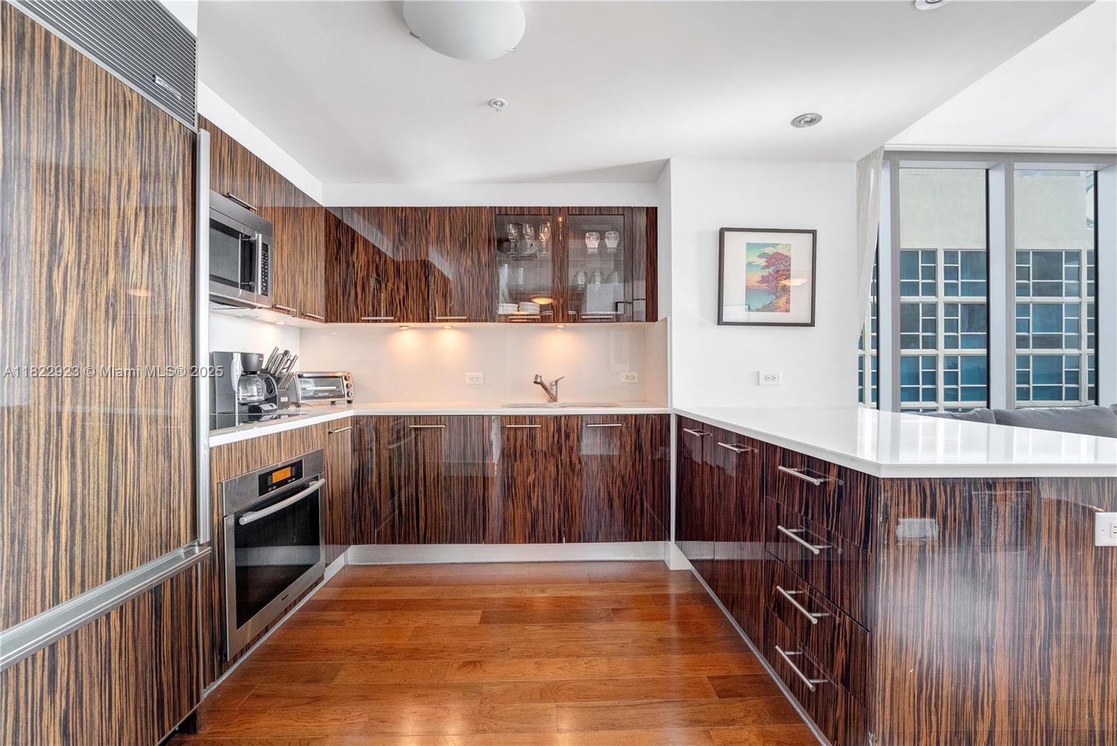 6899 Collins Avenue, Unit 1409 Miami Beach, FL 33141 - Photo 26 of 35 a kitchen with wooden cabinets and a sink