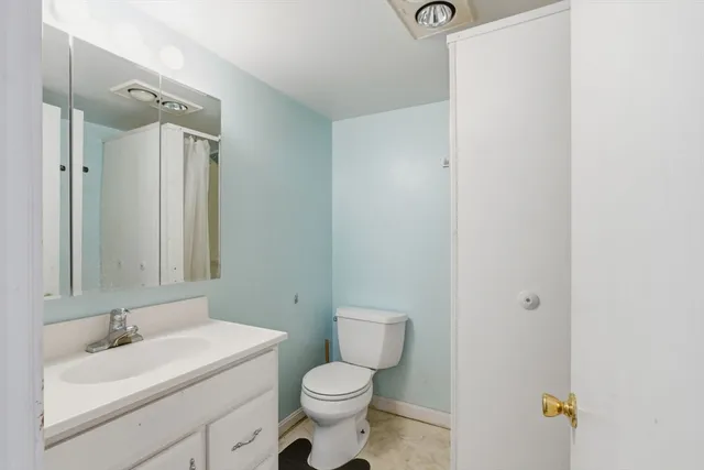 a bathroom with a toilet sink vanity and mirror