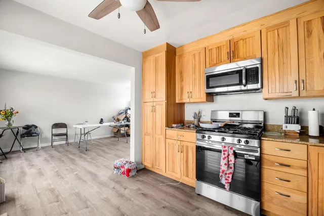 a kitchen with stainless steel appliances granite countertop a stove top oven a sink dishwasher and cabinets with wooden floor