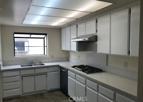 a kitchen with granite countertop a sink a stove and cabinets