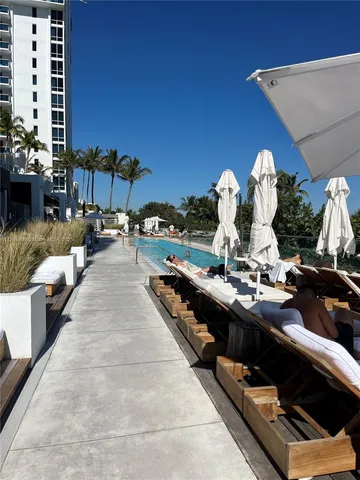 a view of a patio with table and chairs under an umbrella with a barbeque