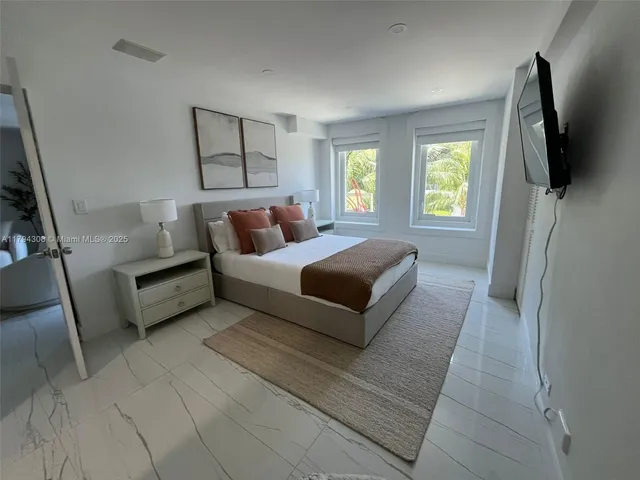 a spacious bedroom with a bed a couch and a flat tv screen on the dresser
