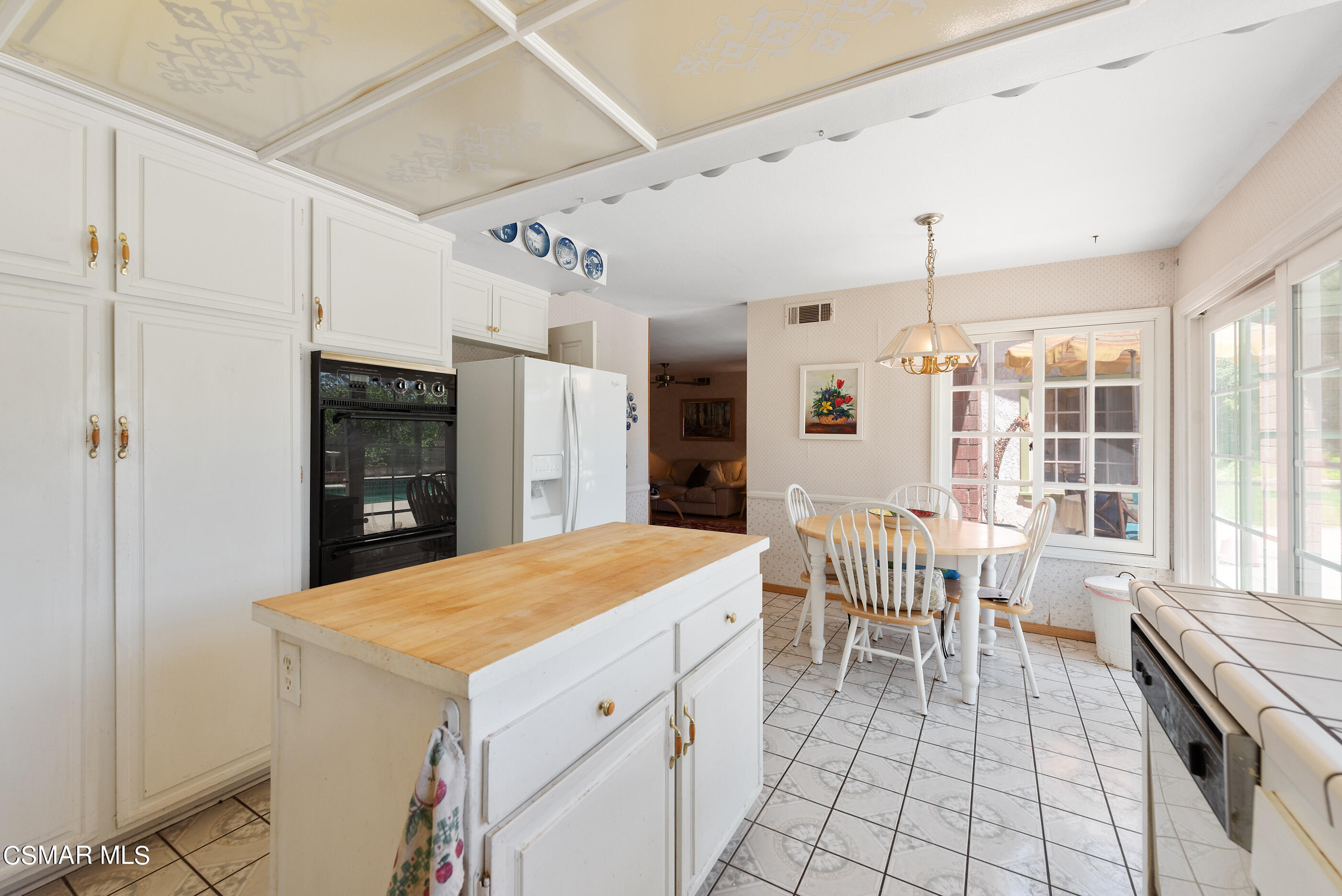 4230 Roxbury Street Simi Valley, CA 93063 - Photo 16 of 40 a kitchen with a stove a refrigerator and a dining table