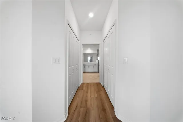 a view of a hallway with wooden floor and a bathroom
