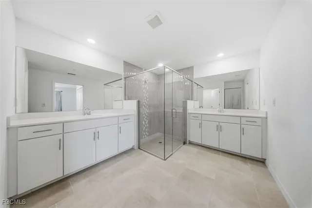 a spacious bathroom with a double vanity sink a mirror and a shower