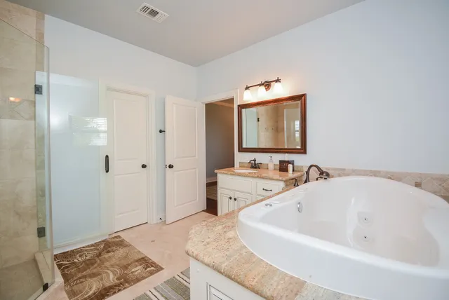 a bathroom with a granite countertop tub sink and mirror