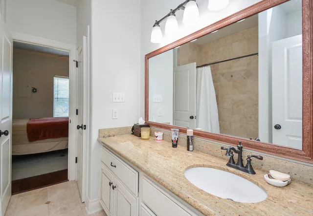 a en suite bathroom with a granite countertop sink and a mirror