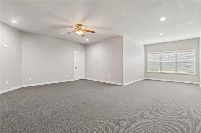 an empty room with windows and ceiling fan